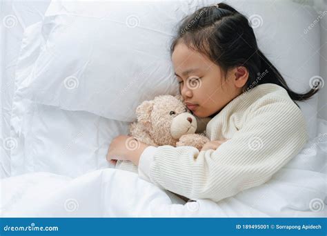Asian Little Girl Sleeping And Hug Teddy Bear In The Bedroom Stock