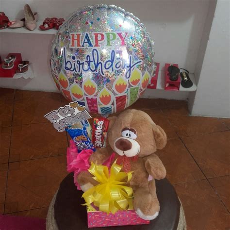 Arreglo sobre una caja con peluche globo metálico y golosinas