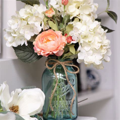 Blue Vintage Mason Jar Filled With Creamy White Hydrangeas And Coral