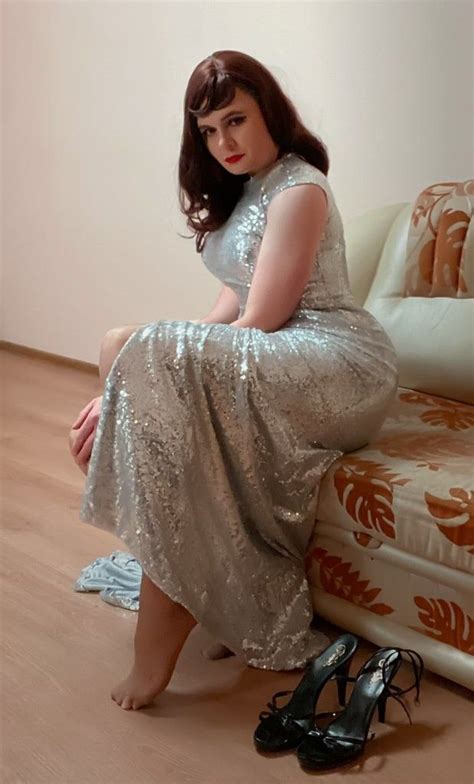 A Woman In A Silver Dress Sitting On A Couch