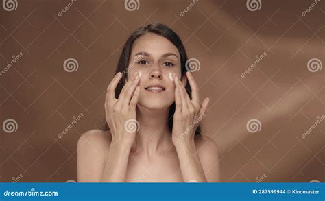 A Woman Takes Care Of Her Skin Applies Cream On Her Face Portrait Of