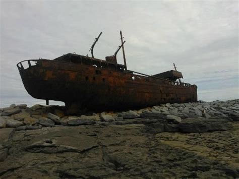 An Old Rusted Boat Sitting On Top Of Rocks