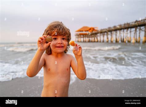 Niño lindo y feliz sosteniendo conchas en la playa Lindo niño en la playa tropical sosteniendo