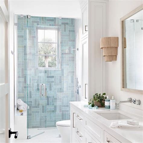 A White Bathroom With Blue Tile On The Walls And Floor Along With A