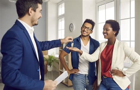 Realtor Or Real Estate Agent Gives Keys To New House To Happy Young