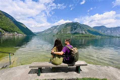 Couple Sitting On Bench Over Austrian Alps Lake In Hallstatt