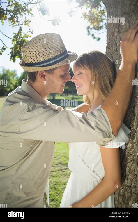 Cute Couple Leaning Against Tree In The Park Stock Photo Alamy