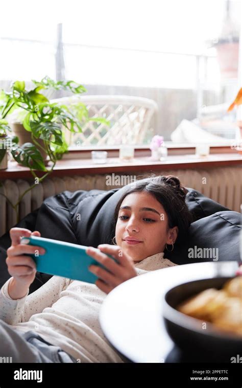 Girl Lying On Bean Bag And Playing Video Games Stock Photo Alamy