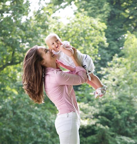 Retrato De Una Madre Feliz Que Juega Con El Bebé En El Parque Imagen De