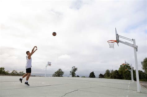 Male Teenage Basketball Player Throwing Ball Toward Basketball Hoop