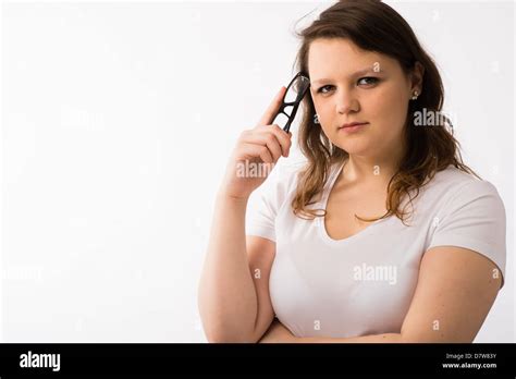 A Young Brunette Teenage Caucasian Girl Tapping Her Head With A Pair Of
