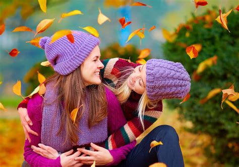 Smiling Friends Having Fun Together In Autumn Park Among Falling Leaves