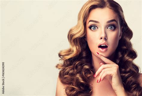 shocked and surprised girl presenting your product curly hair woman amazed beautiful girl