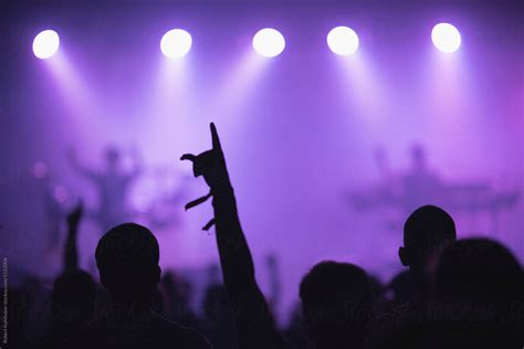 sillhouettes of concert crowd in front of bright stage lights by stocksy contributor robert