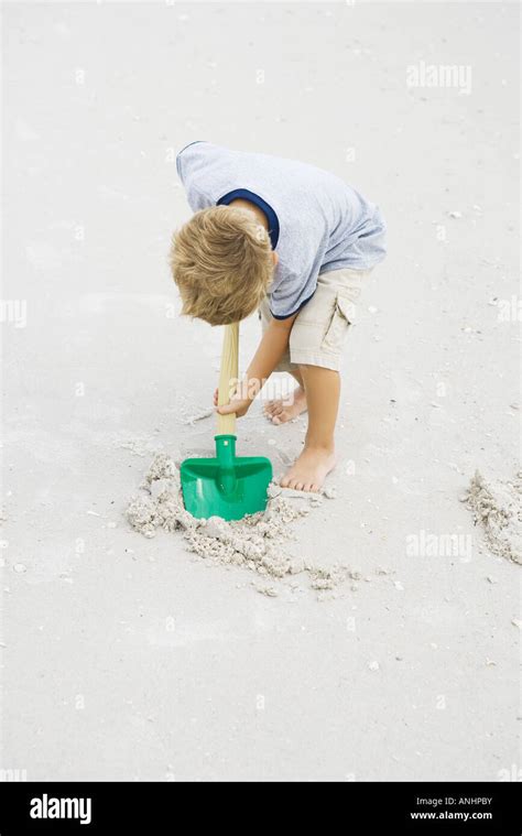 Young Boy Digging In Sand With Shovel Full Length Stock Photo Alamy