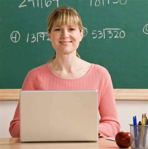 teacher posing with laptop in school classroom teacher posing with laptop at de aff laptop