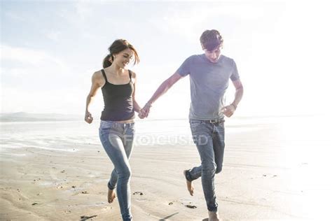 Couple Running Whilst Holding Hands On Beach Love Two Stock Photo