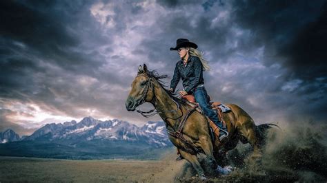 Download Cowgirl Riding A Horse Through Storm Wallpaper