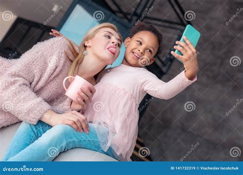 Mother Showing Her Tongue While Making Photo With Daughter Stock Image