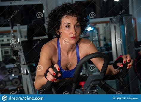Woman Seriously Exercising In The Gym Using The Exercise Bike Stock