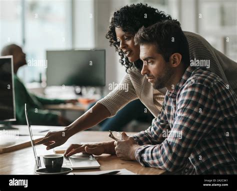 Two Designers Working On A Computer Together In An Office Stock Photo