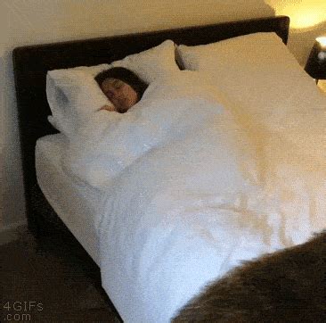 There Is A Bed With White Sheets And Pillows On It Which Has A Person