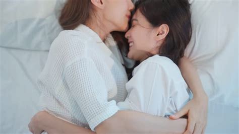 Asian Beautiful Lesbian Couple Lying Down On Bed And Kiss On Forehead By Skawee