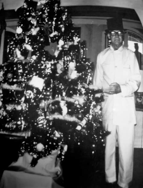 A Man Standing Next To A Christmas Tree
