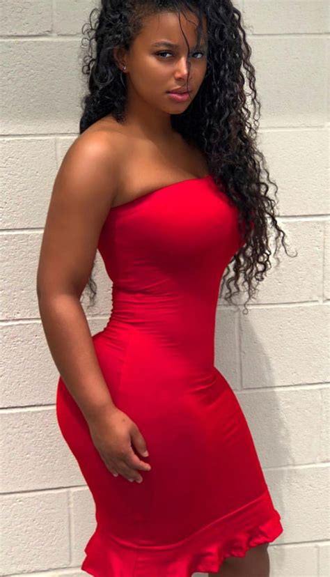 a woman in a red dress posing for the camera with her hands on her hips