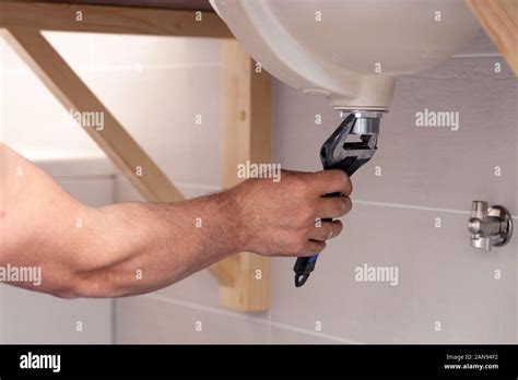 Closeup Male Plumbers Hand Fixing Sink In Bathroom With Tile Wall