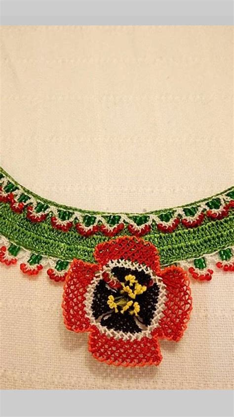 A Red And Green Beaded Necklace On A White Shirt With Flowers In The Center