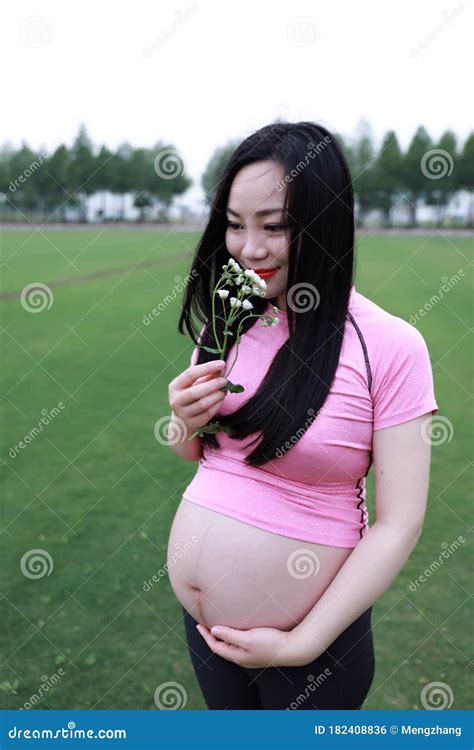 Asian Chinese Pregnant Woman In Yoga Dress In Nature Outdoor Smell The Flower On Hand Restful