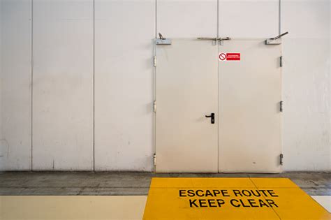 Emergency Exit Door With Keep Clear Warning Message On Floor Stock