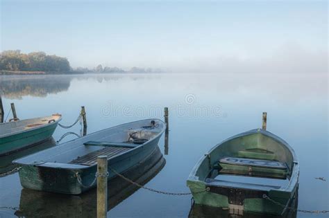 A Lake Some Rowboats Are Moored And On The Lake There Is Fog And The