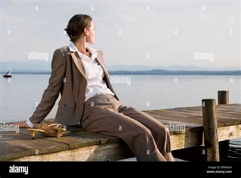 Woman Sitting On Pier At Lake Stock Photo Alamy