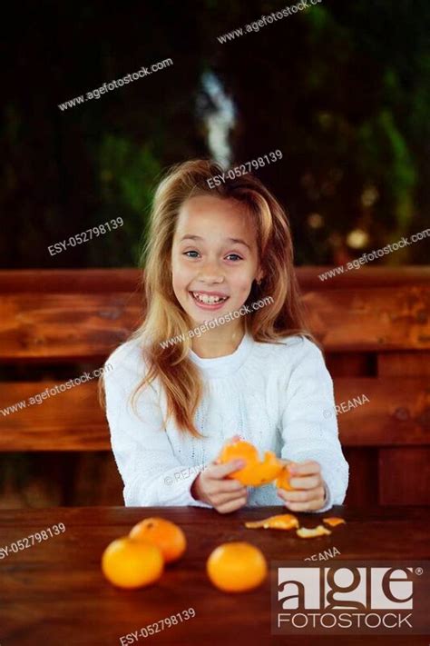 Happy Preteen Girl Is Peeling Fresh Tangerine Stock Photo Picture And Low Budget Royalty Free