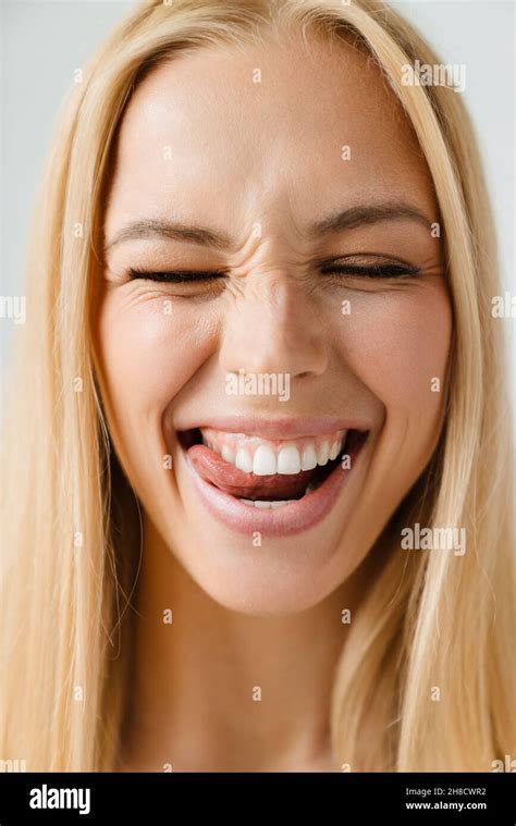 Young Blonde Woman Smiling While Licking Her Teeth Isolated Over White