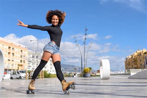 Black Woman On Roller Skates Riding Outdoors On Urban Street Stock