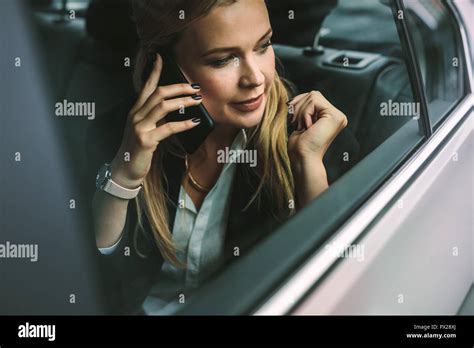 Young Businesswoman Talking On The Cellphone While Sitting On Back Seat