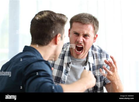 Two Angry Friends Or Roommates Arguing And Threatening In The Living