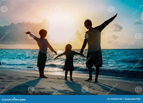 Padre Con Siluetas De Hijo E Hija Juegan En La Playa Al Atardecer Foto