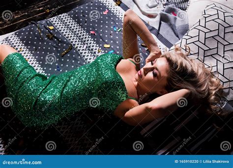 Beautiful Woman In Elegant Red Dress Lying On Modern Sofa Stock Photo