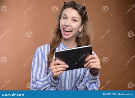 Portrait Of A Cheerful Charming Girl Holding A Digital Tablet With A Toothy Smile Wearing A