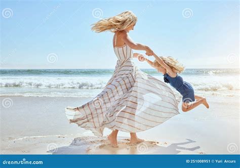 Happy Mother Swinging And Spinning Cute Daughter In Circles By The Arms At The Beach Playful