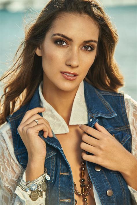 A Woman Wearing A Denim Vest And White Shirt Is Posing For The Camera