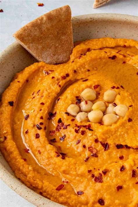 A Bowl Filled With Hummus And Some Crackers