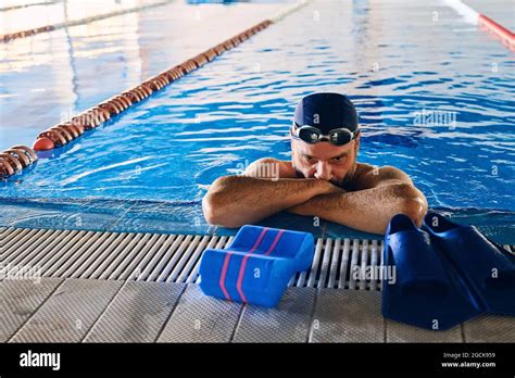 Tired Male Swimmer Leaning On Edge Of Pool And Having Break During