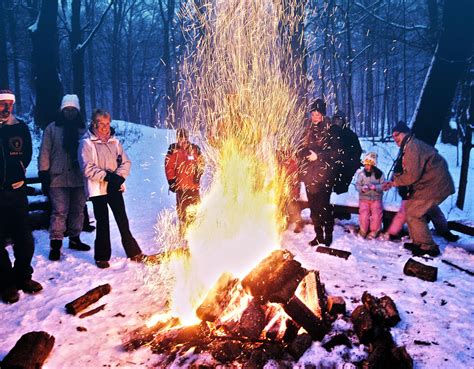 A Group Of People Standing Around A Fire In The Snow