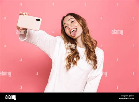 Portrait Of A Happy Young Woman Taking Selfie With Mobile Phone Isolated Over Pink Background