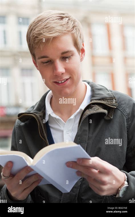 Young Cheerful Handsome Guy Reading A Book With Blank Cover Stock Photo